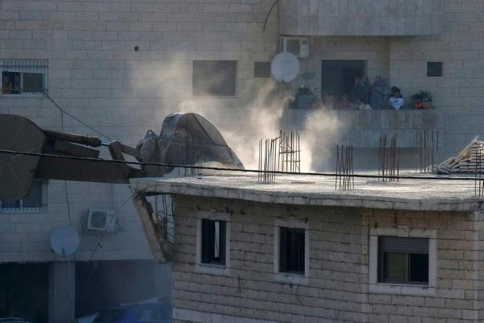 A Palestinian family watches Israeli security forces as they demolish a Palestinian buildings in the Jerusalem area on July 22, 2019