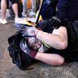 A protester is detained by police during a demonstration in Hong Kong. Police say they will charge dozens with rioting in the wake of recent violence
