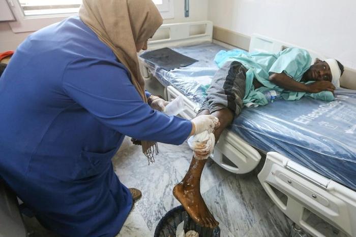 A nurse cleans the wound of a wounded migrant at a medical emergency ward in a Tripoli hospital on Wednesday