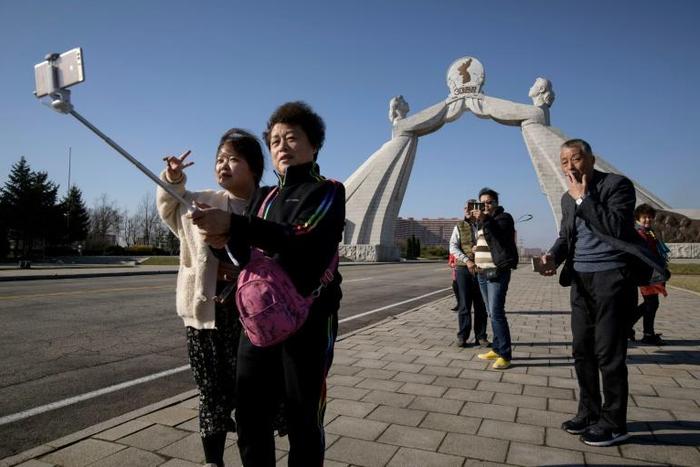 Tourists from China pose for photos before the Three Charters monument in the North Korean capital Pyongyang