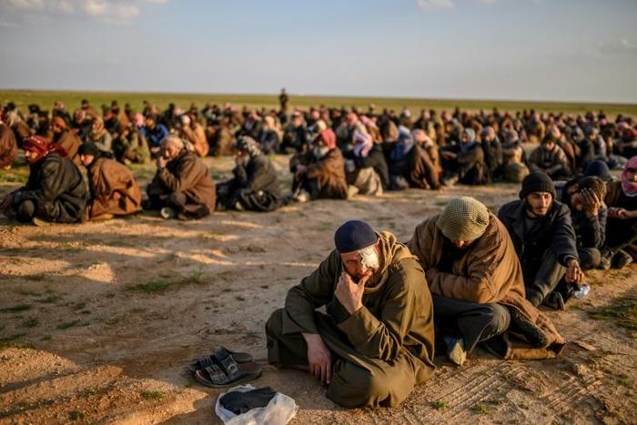 Suspected Islamic State fighters wait to be searched by members of the Kurdish-led Syrian Democratic Forces