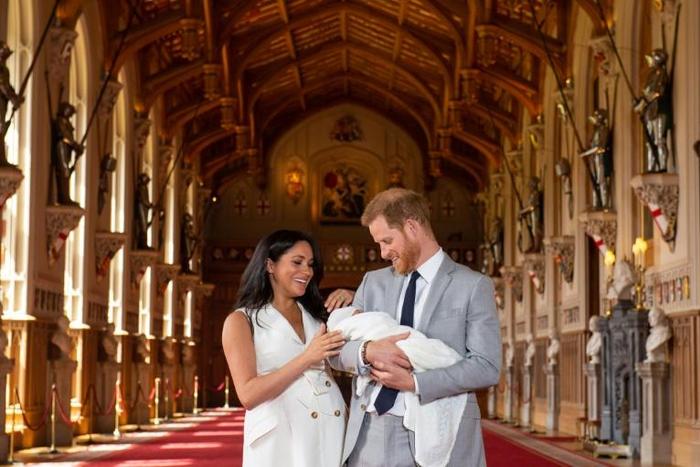 Britain's Prince Harry, Duke of Sussex (R), and his wife Meghan, Duchess of Sussex, pose with their newborn baby son, Archie Harrison Mountbatten-Windsor, in St George's Hall at Windsor Castle