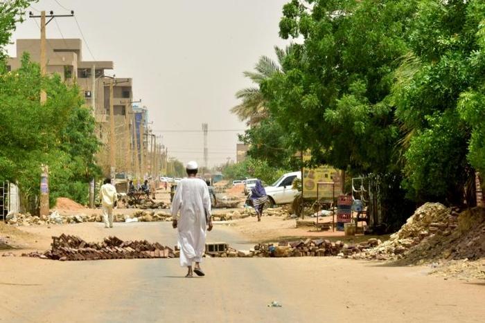 Residents walk past barricades in the Sudanese capital
