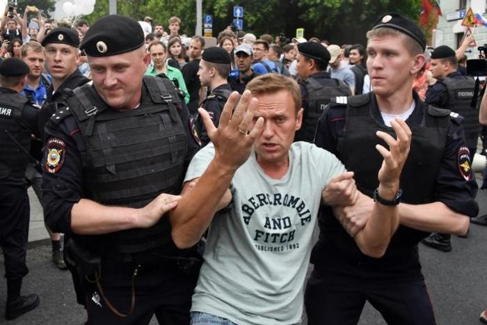 Opposition leader Alexei Navalny is detained by Russian police officers during a Moscow march to protest against polie abuse