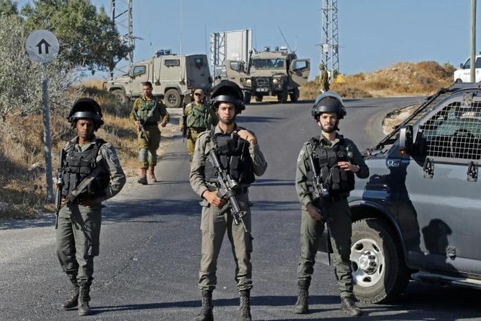 Israeli soldiers stand guard next to the site where the soldier's body was found near the settlement of Migdal Oz in the occupied West Bank
