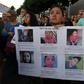 A woman holds photos of migrant children who have died in US custody as people protest in LA against the upcoming ICE raids and detentions of refugee asylum seekers