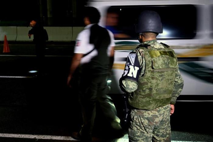 Watched by a member of Mexico's new National Guard (R), a Mexican Migration officer waits for undocumented migrants at a checkpoint on the outskirts of Tapachula, Chiapas state, Mexico, near the border with Guatemala, on June 19, 2019