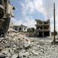 A picture taken on June 14, 2019, shows people gathering next to a damaged building in the town of Ihsim, in Syria’s Idlib region, scene of heavy bombardments by Syrian government forces and its ally Russia