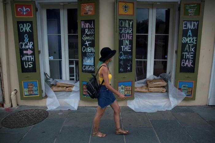 A woman walks past a cigar lounge and bar protected by sand bags in the French Quarter of New Orleans, in preparation for tropical storm Barry