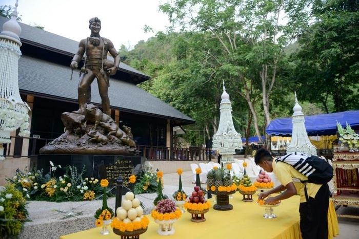 A member of the "Wild Boars" football team places flowers in front of a statue of Saman Gunan, the Thai navy diver who died during the rescue of the team from the Tham Luang cave