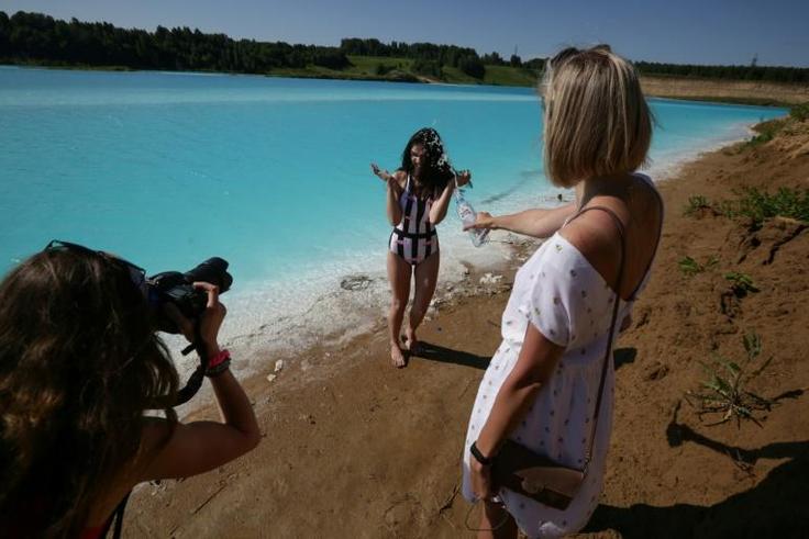 A young woman poses for pictures by the ash dump site -- nicknamed the local "Maldives" -- but what appears a tropical paradise is actually a toxic lake