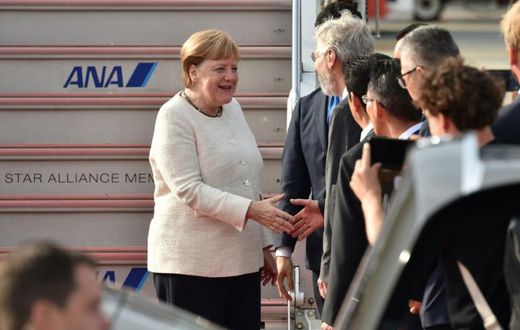 Germany's Chancellor Angela Merkel (L) is greeted by well-wishers upon her arrival in Japan for the G20 summit as officials sought to play down fears over her health