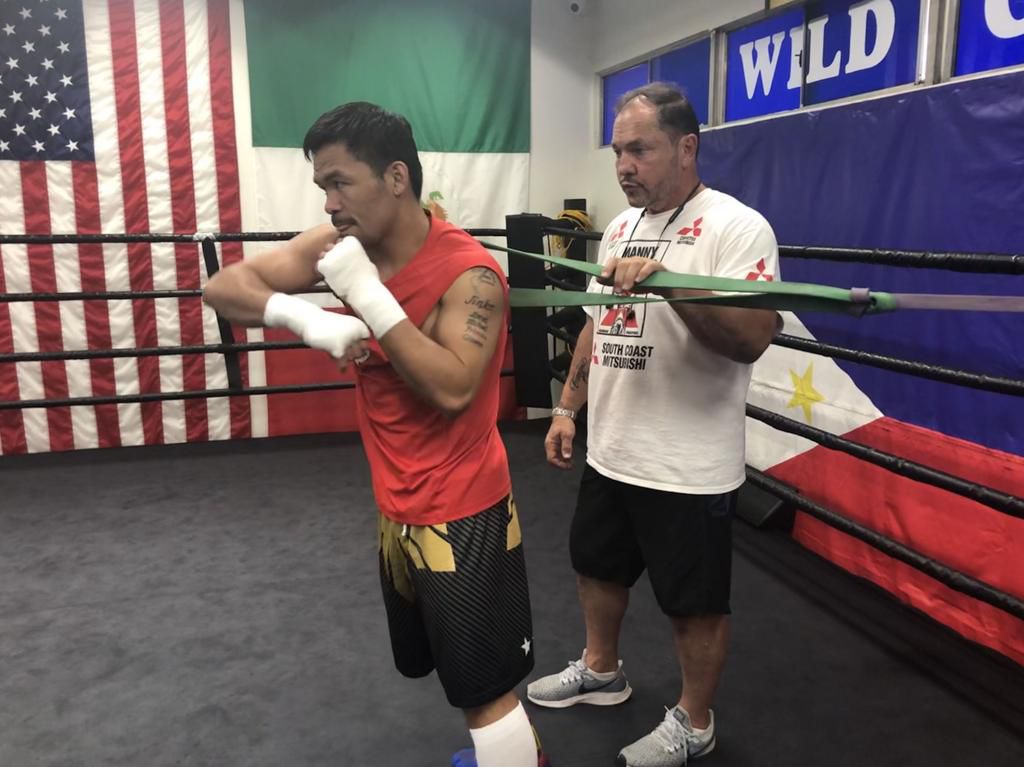 Pacquiao testing a resistance band with coach Justin Fortune.
