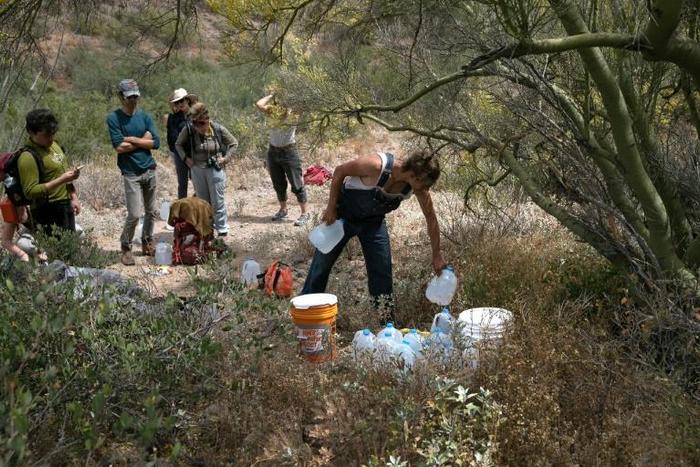 A volunteer for the humanitarian aid organization No More Deaths delivers water along a trail used by undocumented immigrants in the desert near Ajo, Arizona