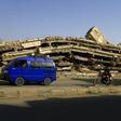 A van drives by a building flattened in Saudi-led coalition air strikes in Amran, 50 kilometres (30 miles) north of the Yemeni capital Sanaa