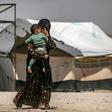 A woman carries a child in Al-Hol, one of three camps in Syria where 50 to 60 Belgian children of jihadists reside