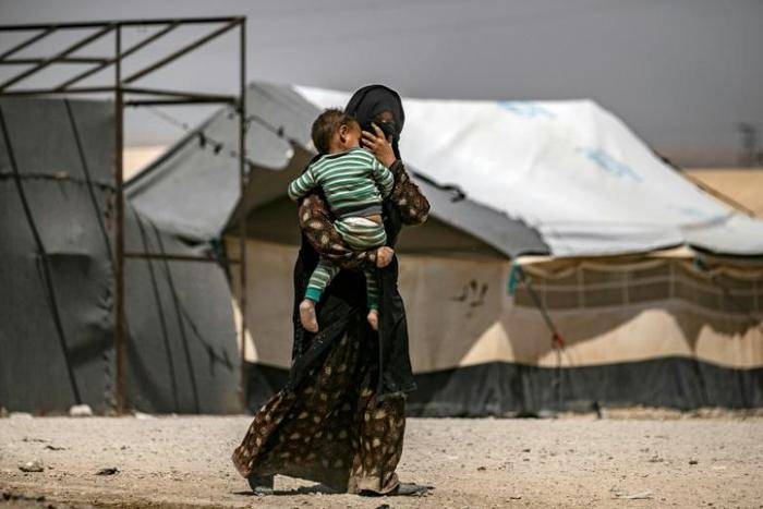 A woman carries a child in Al-Hol, one of three camps in Syria where 50 to 60 Belgian children of jihadists reside