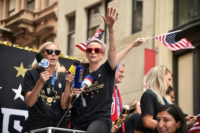 World Cup star Megan Rapinoe waves a US flag as the US women's World Cup-winning soccer team is feted with a ticker tape parade in New York