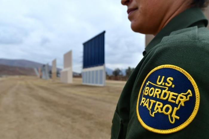 A US Border Patrol officer stands near prototypes of President Donald Trump's proposed wall, in San Diego, California in November 2017