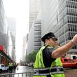A policeman gestures near fire trucks after a helicopter crash-landed on top of a building in midtown Manhattan on June 10, 2019
