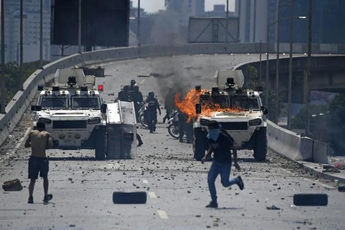 Supporters of Venezuelan opposition leader and self-proclaimed acting president Juan Guaido clash with forces loyal to President Nicolas Maduro in front of La Carlota military base in Caracas on April 30, 2019