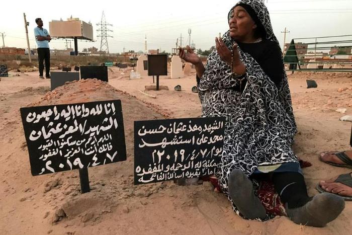 A Sudanese mother, Khadom, mourns at the grave of her son Al-Moez, who was killed when a bullet pierced the window of his workplace during anti-government demonstrations in April