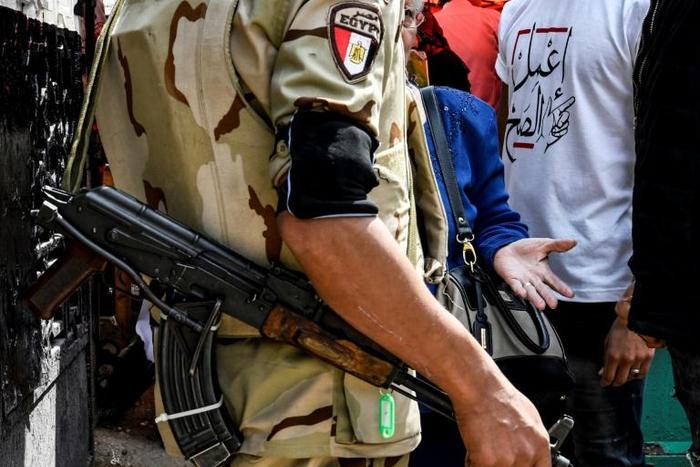 An Egyptian soldier speaks with a woman, as a youth behind her wears a t-shirt that reads "do the right thing", in Shubra on April 20, 2019; Egypt's parliament has approved amendments to a law that rights groups say imposes strict curbs on NGOs