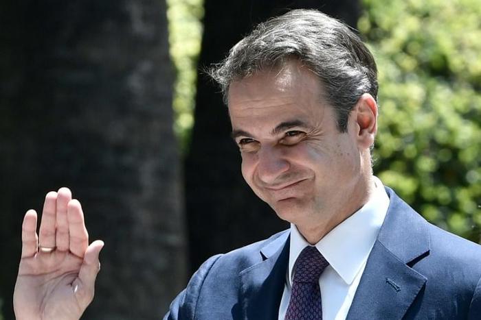 Greece's Prime Minister Kyriakos Mitsotakis waves as he leaves the presidential palace in Athens after being sworn in