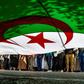 In this file photo from late May, Algerian protesters are seen from underneath a giant national flag