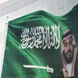 Saudi King Salman and his son Crown Prince Mohammed appear next to a Saudi flag on a billboard in Riyadh