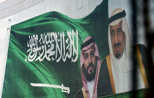 Saudi King Salman and his son Crown Prince Mohammed appear next to a Saudi flag on a billboard in Riyadh