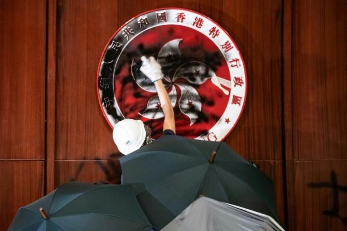 A protester daubs black paint over the Hong Kong emblem in parliament after breaking into the government headquarters