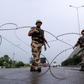 Security personnel stand guard at a roadblock on a near-deserted street in Jammu, Kashmir