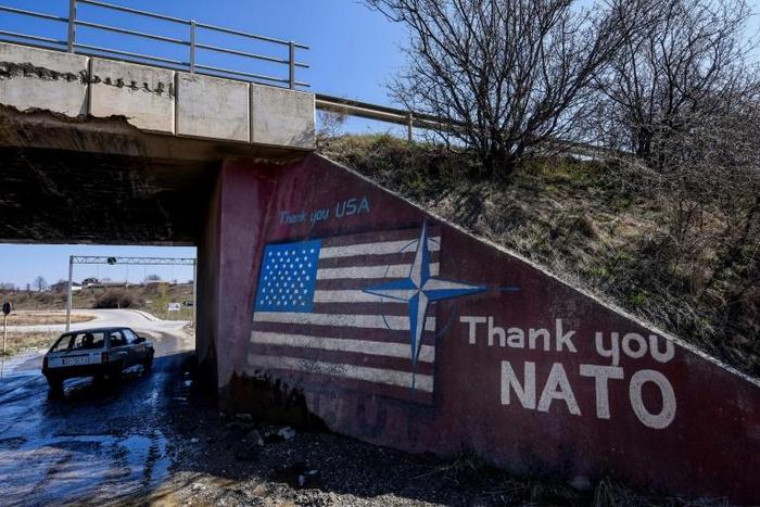 A car drives past graffiti reading "Thank You NATO" and featuring the US flag near the village of Stagovo, Kosovo on March 24, 2019, 20 years after the start of the alliance's bombing campaign