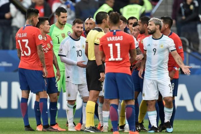 Paraguayan referee Mario Diaz de Vivar is surrounded by players after showing the red card to Argentina's Lionel Messi and Chile's Gary Medel during the Copa America third-place play-off