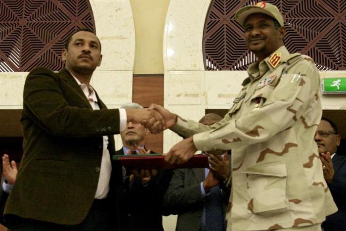 Sudanese deputy chief of the ruling miliary council Mohamed Hamdan Dagalo and protest movement Alliance for Freedom and Changes leader Ahmad al-Rabiah shake hands after inking a power-sharing agreement