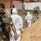 A Lebanese army soldier walks past military intelligence forensic investigators ar the scene where two drones came down in the vicinity of a media centre of the Shiite Hezbollah movement