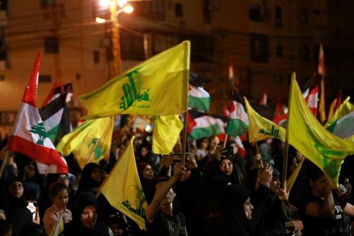 Lebanese sympathizers of the Shiite Hezbollah party wave Lebanese national and party (yellow) flags, as they march in a southern suburb of the capital Beirut