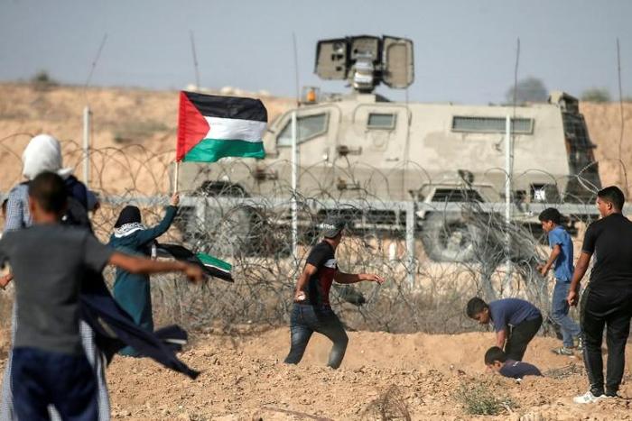 Palestinian demonstrators throw stones at Israeli security forces during protests along the border with Israel east of Khan Yunis, in the southern Gaza Strip