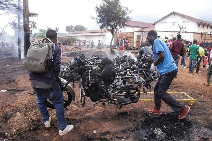 Two men carry a smouldering motorbike from the site of Sunday's blast