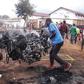 Two men carry a smouldering motorbike from the site of Sunday's blast