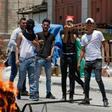 Stone-carrying Palestinians near Hebron stand behind a burning tyre as they protest against a US-led Middle East conference in Bahrain