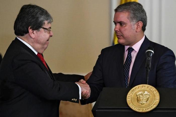 Colombian President Ivan Duque (R) shakes hands with Colombian Foreign Minister Carlos Holmes Trujillo during the signing of a decree that allows the nationalization of 24,000 children of Venezuelan parents born in Colombia August 5, 2019