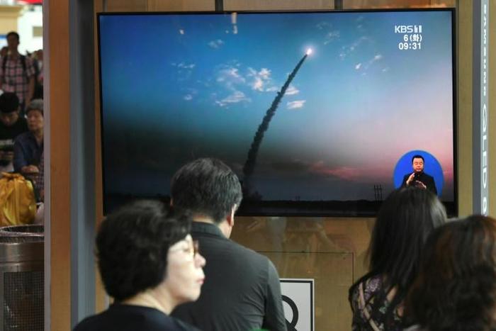 People watch a television news screen showing a file footage of North Korea's missile launch, at a railway station in Seoul on August 6, 2019