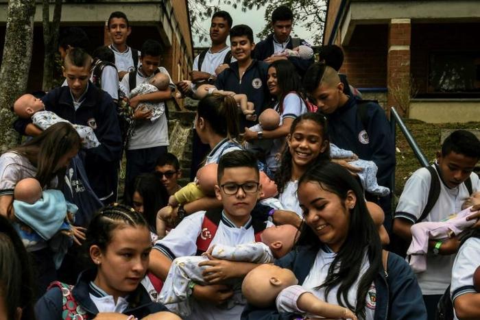 Students carry their "babies" during a break at a school in Caldas municipality, Colombia on May 17, 2019