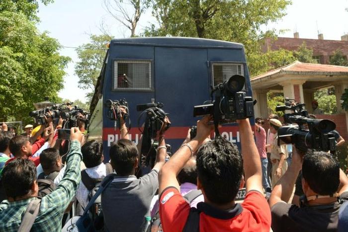 Indian media gather around a police vehicle carrying seven men accused of the brutal rape and murder of an eight-year-old nomadic girl