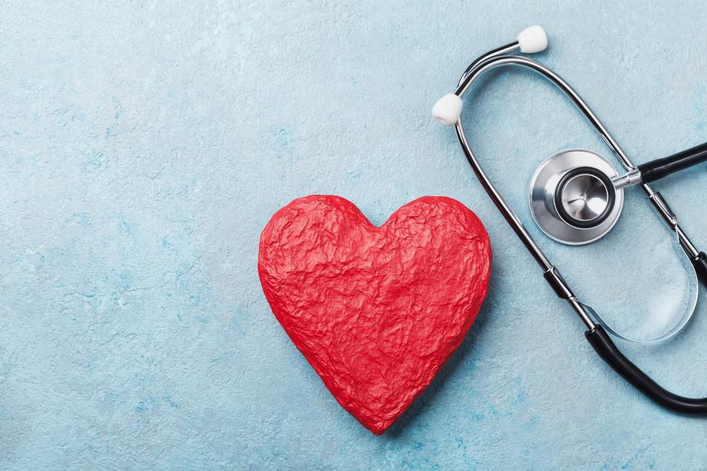 Red heart shape and medical stethoscope on blue background top view. Health care, medicare and cardiology.