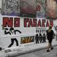 Women walk past a recent graffiti in Athens' historic district of Exarchia