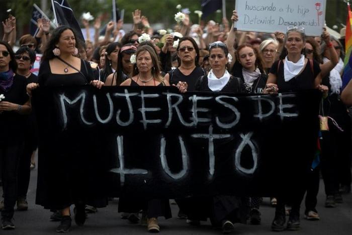 Women dressed in black march to the presidential palace in Santiago demanding justice for those killed and injured during two weeks of protests