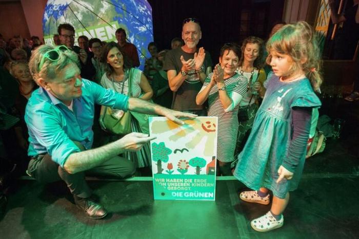 Austrian Green party head Werner Kogler holds a placard reading 'We only borrowed the earth from our children' after the exit poll results came in on Sunday